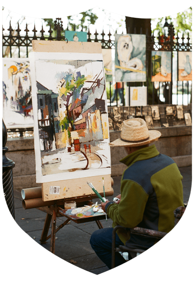 A painter sits in front of a canvas outdoors