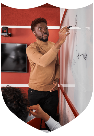 An online MEd student stands at a whiteboard with a marker