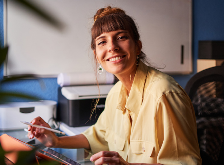 An online MEd student sits at a desk in an office