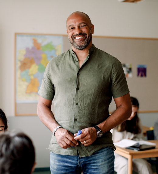 A successful online MEd student stands in a classroom as a teacher