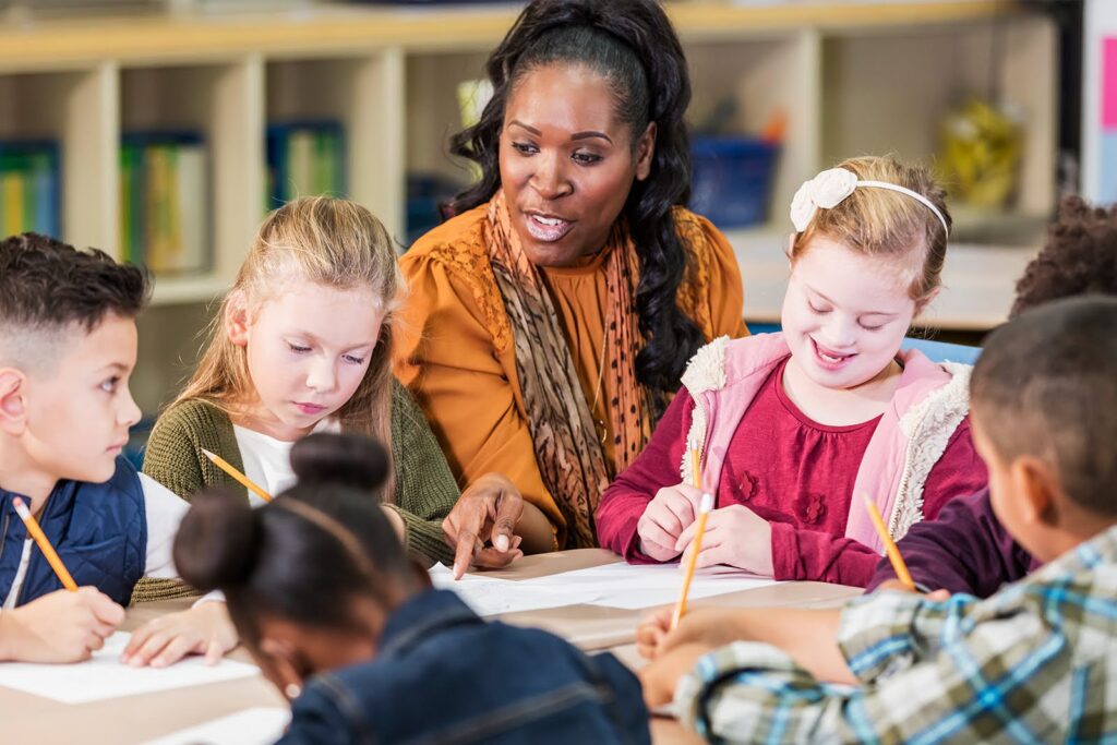 A teacher helps a group of students complete worksheets.